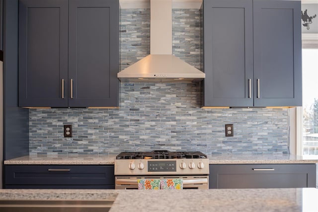 6001 N Silver Pines Dr, Bellaire, MI 49615 - kitchen featuring light stone counters, wall chimney range hood, stainless steel gas range, and decorative backsplash