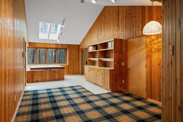 1871 Cherry Hill Ct, Harbor Springs, MI 49740 - interior space with vaulted ceiling with skylight, baseboards, wooden walls, and light colored carpet