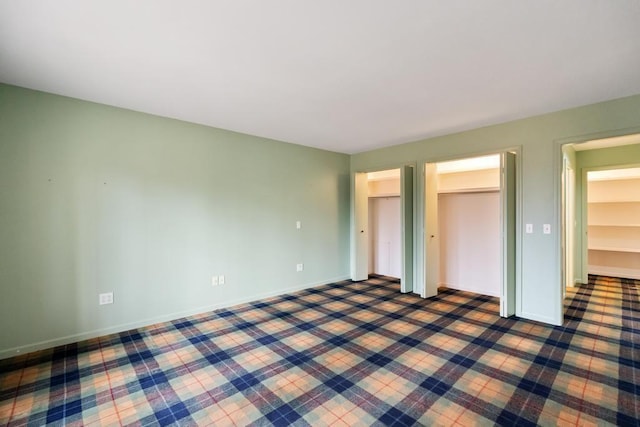 1871 Cherry Hill Ct, Harbor Springs, MI 49740 - unfurnished bedroom featuring two closets, baseboards, and dark colored carpet