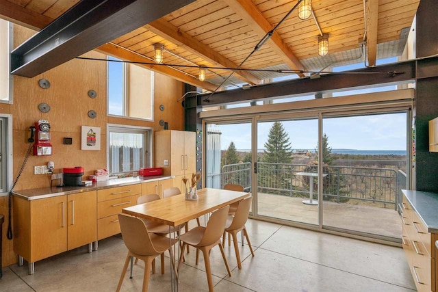 dining area with high vaulted ceiling, wooden walls, beamed ceiling, finished concrete flooring, and wooden ceiling