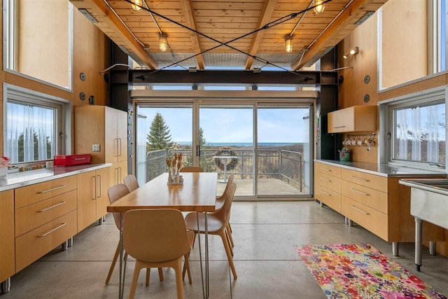 dining area with wood ceiling, concrete flooring, and a high ceiling