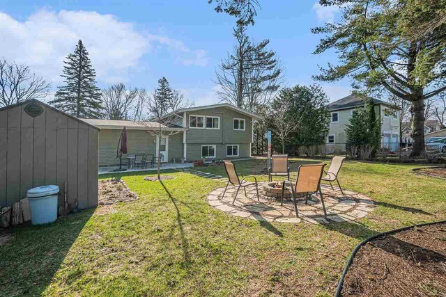 view of yard with an outdoor structure, a fire pit, fence, a patio, and a shed