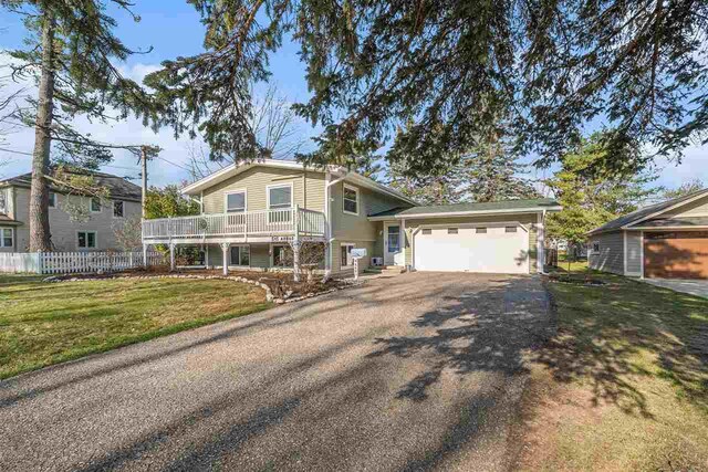 tri-level home with an attached garage, aphalt driveway, fence, and a front yard