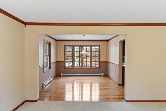 empty room featuring baseboards, wood finished floors, baseboard heating, and ornamental molding