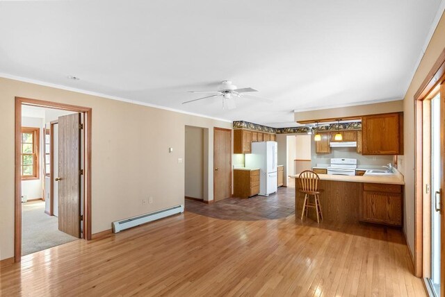kitchen with a baseboard heating unit, a sink, freestanding refrigerator, electric range oven, and under cabinet range hood