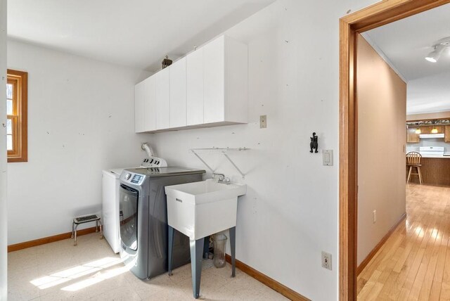 washroom featuring cabinet space, washing machine and clothes dryer, and baseboards