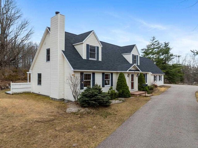 new england style home with a front lawn and a chimney