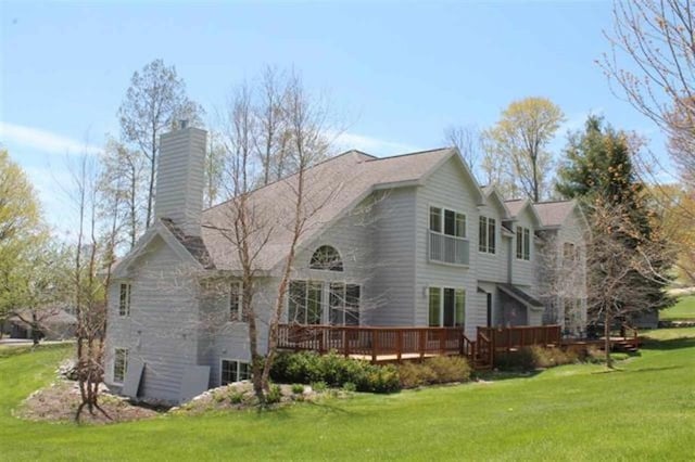 back of house featuring a lawn, a wooden deck, and a chimney