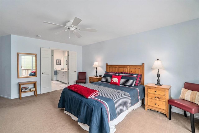 bedroom featuring a ceiling fan, baseboards, light colored carpet, and ensuite bath