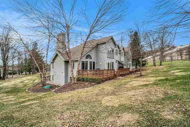 view of side of property with a chimney, a wooden deck, and a yard