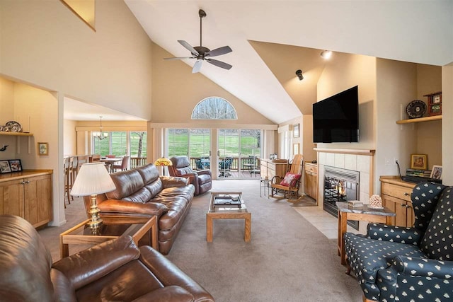 living room with high vaulted ceiling, a tiled fireplace, light colored carpet, and a healthy amount of sunlight