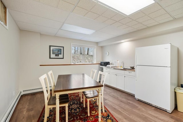 8913 Horseshoe Dr, Harbor Springs, MI 49740 - dining space with a paneled ceiling, baseboard heating, and light wood-type flooring