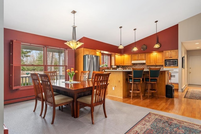 8913 Horseshoe Dr, Harbor Springs, MI 49740 - dining space featuring high vaulted ceiling, light wood-style flooring, and baseboard heating