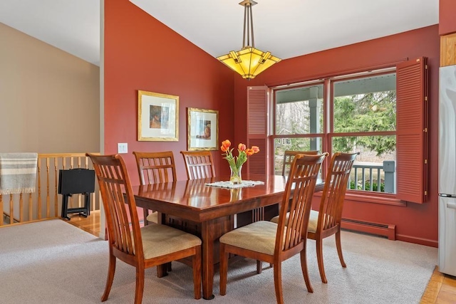 8913 Horseshoe Dr, Harbor Springs, MI 49740 - dining room featuring vaulted ceiling, baseboard heating, light carpet, baseboards, and light wood-type flooring