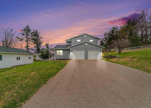 traditional-style house with a lawn, fence, an attached garage, and driveway