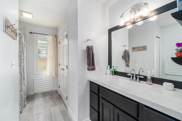 bathroom featuring baseboards, visible vents, wood finished floors, and vanity