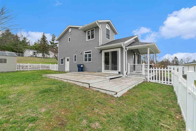 back of house featuring a storage shed, a deck, a fenced backyard, an outbuilding, and a yard