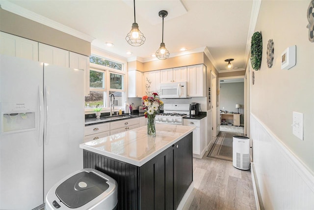 kitchen with white appliances, crown molding, a sink, and white cabinets