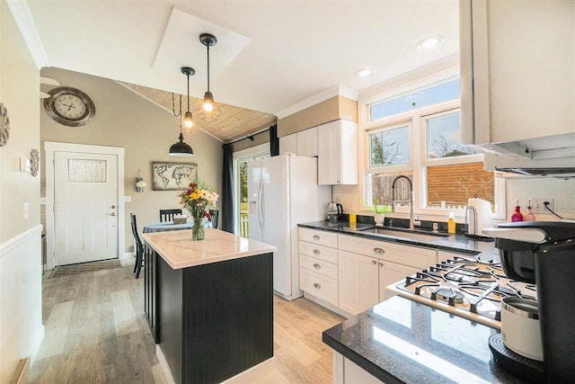 kitchen featuring white refrigerator with ice dispenser, white cabinets, a sink, and a center island