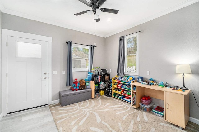 recreation room with crown molding, baseboards, a ceiling fan, and wood finished floors