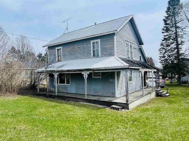 rear view of property featuring a lawn, covered porch, and metal roof