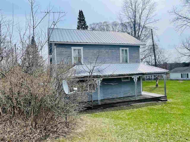back of house with a lawn, a deck, and metal roof