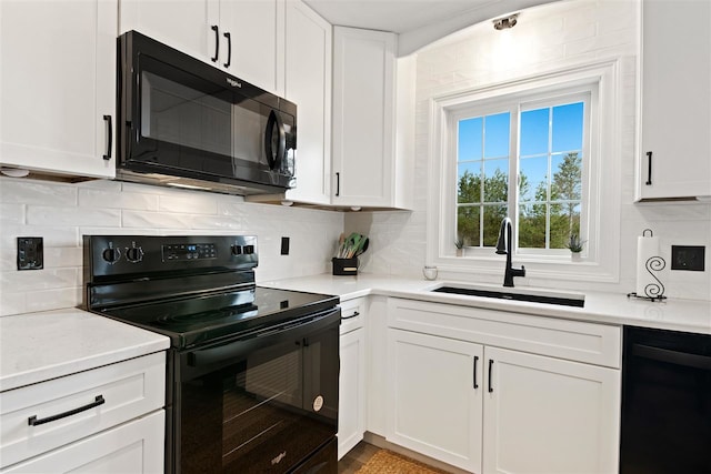 kitchen with a sink, white cabinets, black appliances, and tasteful backsplash