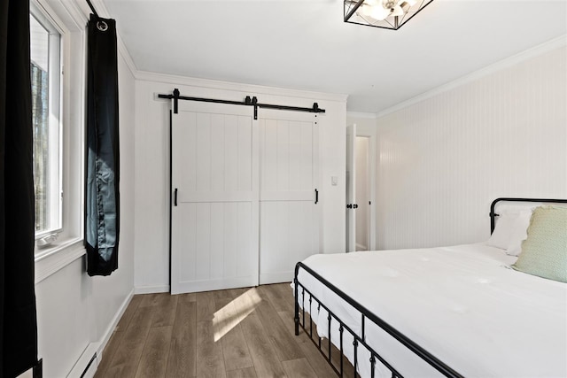 bedroom featuring crown molding, a closet, wood finished floors, baseboards, and a barn door