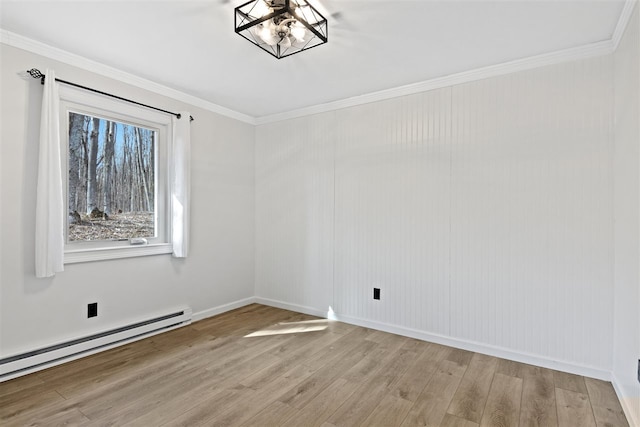 spare room with ornamental molding, baseboards, a baseboard heating unit, light wood finished floors, and a notable chandelier