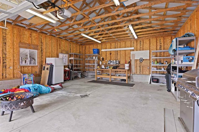 garage featuring a workshop area, a garage door opener, and freestanding refrigerator
