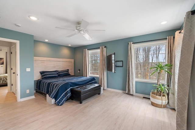 bedroom with baseboards, multiple windows, and wood finished floors