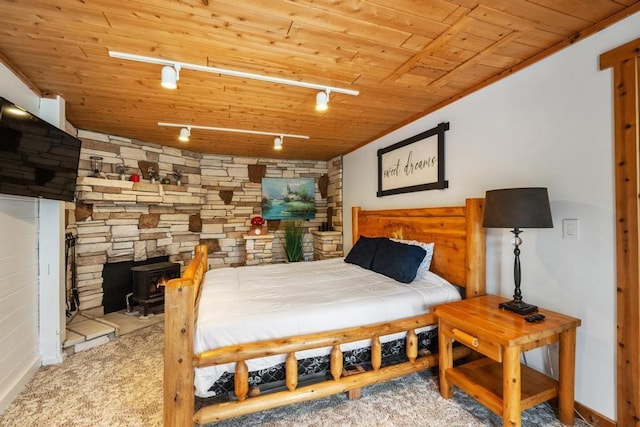 carpeted bedroom featuring baseboards, rail lighting, and wood ceiling