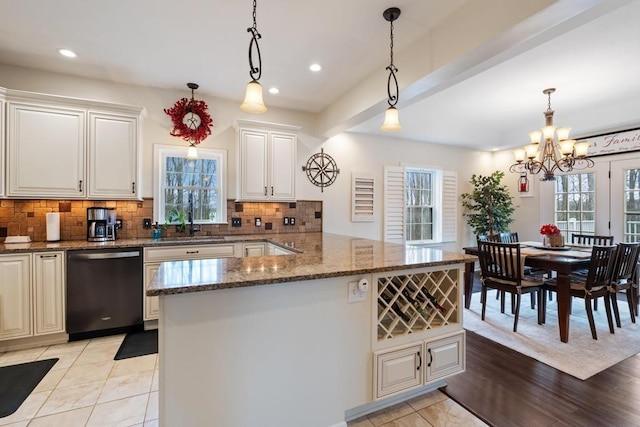 kitchen with an inviting chandelier, tasteful backsplash, a sink, stone counters, and dishwasher