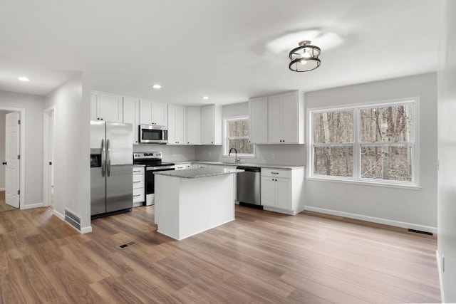 kitchen with baseboards, a sink, appliances with stainless steel finishes, and wood finished floors