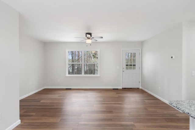 empty room with baseboards, dark wood finished floors, and ceiling fan