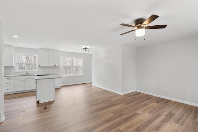 unfurnished living room with baseboards, light wood-style flooring, and ceiling fan