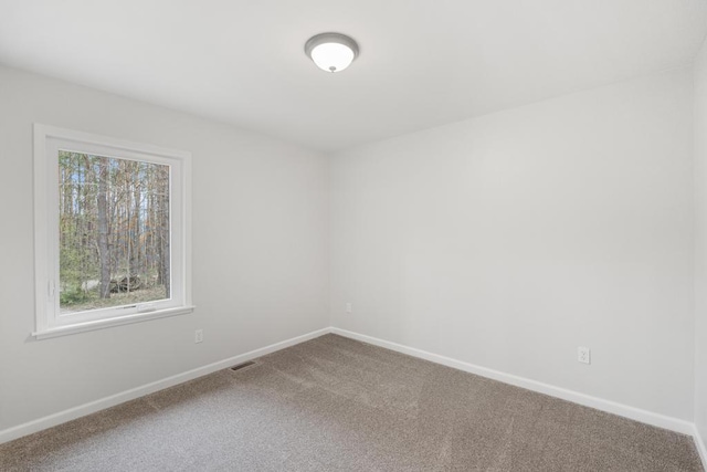 carpeted spare room featuring baseboards and visible vents