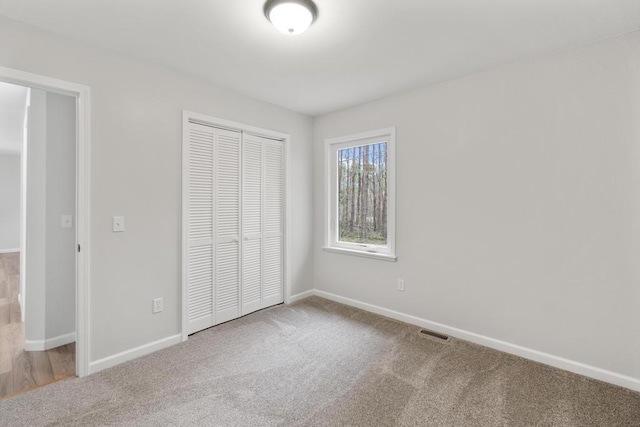 unfurnished bedroom featuring carpet floors, baseboards, visible vents, and a closet