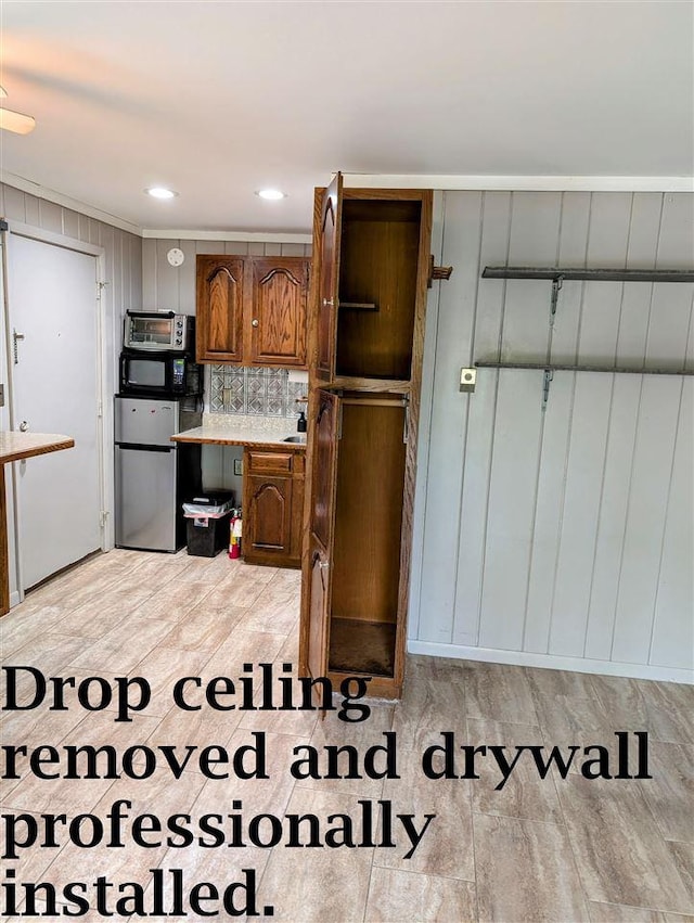 kitchen featuring brown cabinetry, freestanding refrigerator, recessed lighting, light countertops, and light wood-style flooring