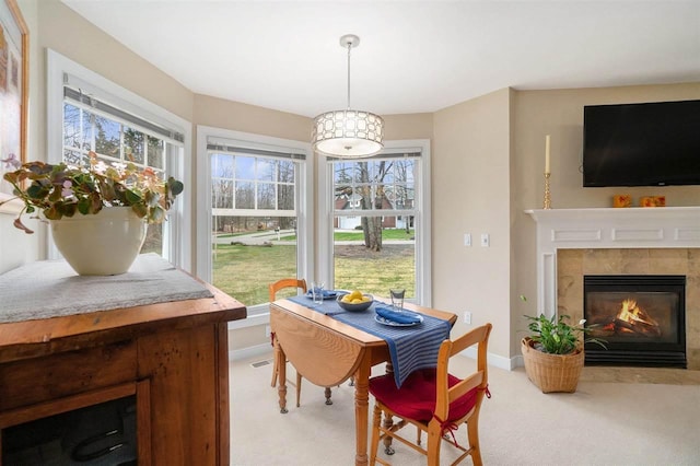 dining area featuring a healthy amount of sunlight, baseboards, light carpet, and a premium fireplace