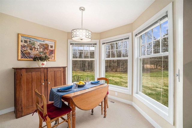 dining space with baseboards, visible vents, and light colored carpet