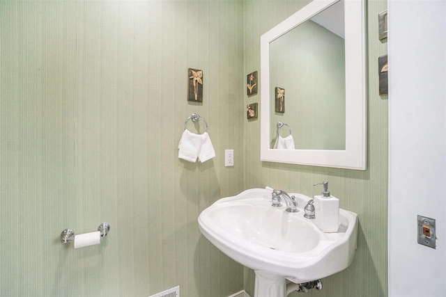 bathroom featuring a sink and wallpapered walls