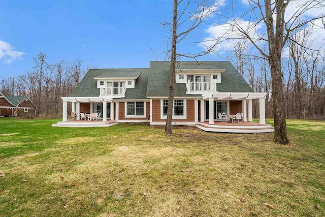 back of property featuring a pergola, a wooden deck, a balcony, a lawn, and a patio