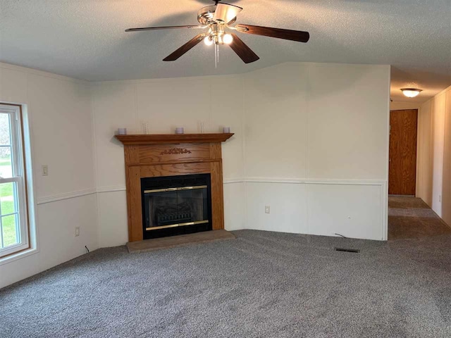 unfurnished living room featuring a healthy amount of sunlight, a glass covered fireplace, and a textured ceiling