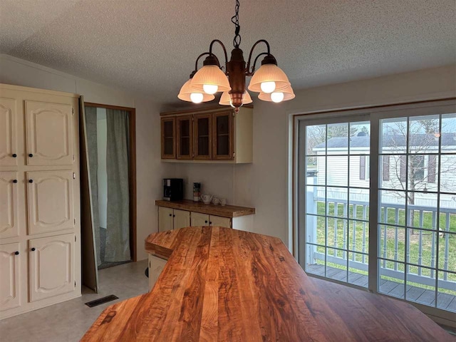 dining area with a textured ceiling, a chandelier, and visible vents