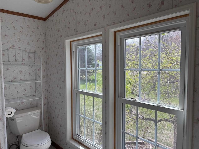 bathroom featuring crown molding, toilet, and wallpapered walls