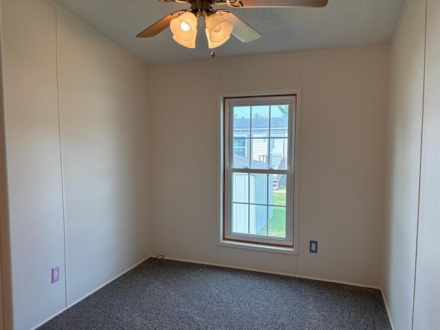 spare room featuring dark carpet, a ceiling fan, baseboards, and plenty of natural light