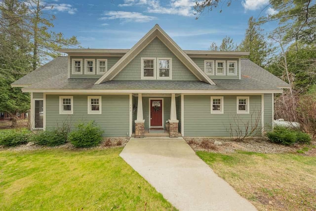 craftsman house featuring a shingled roof, a porch, and a front lawn