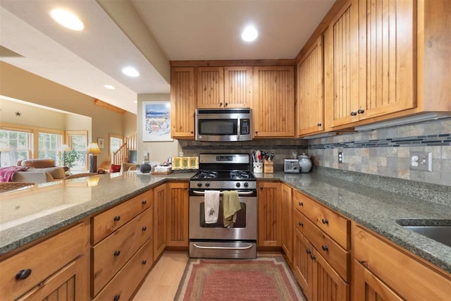 kitchen featuring backsplash, dark stone countertops, open floor plan, stainless steel appliances, and recessed lighting