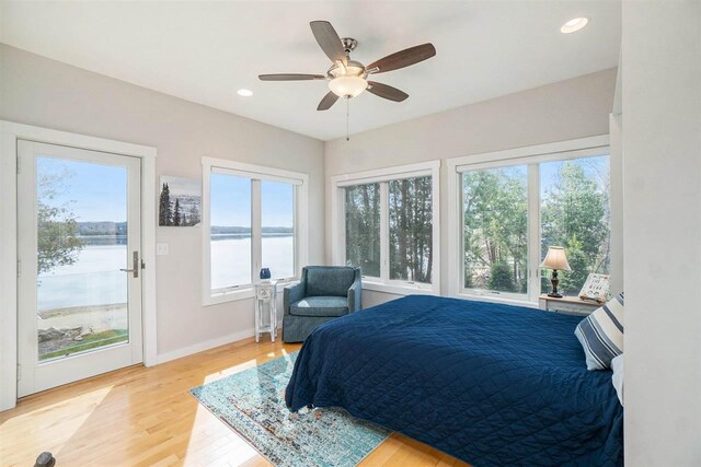 bedroom with light wood-style floors, multiple windows, and access to exterior